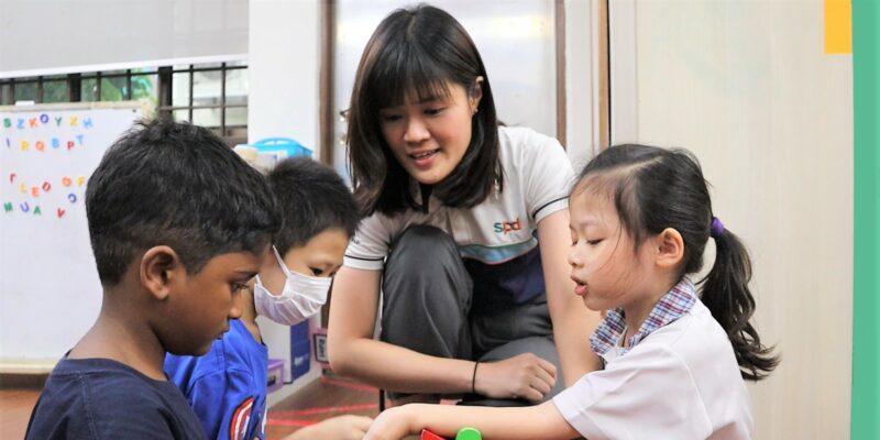 Speech therapist Danica looking on as 3 children play with building blocks