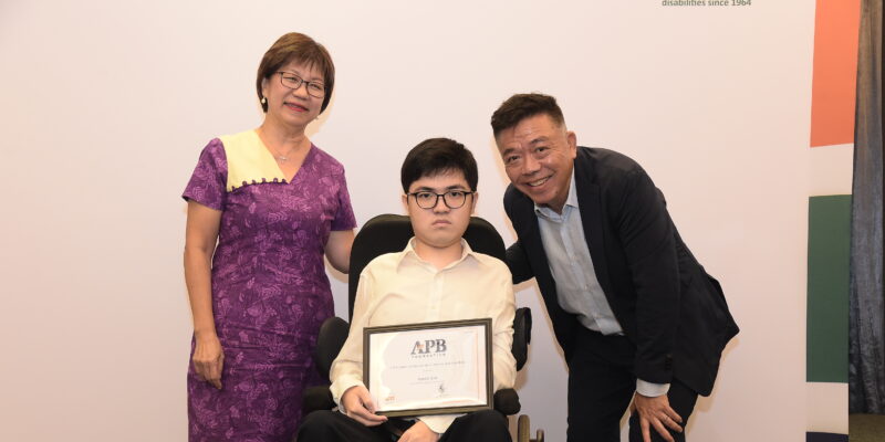 Aaron holding his scholarship, positioned between Ms Denise Phua and Mr Kenneth Choo