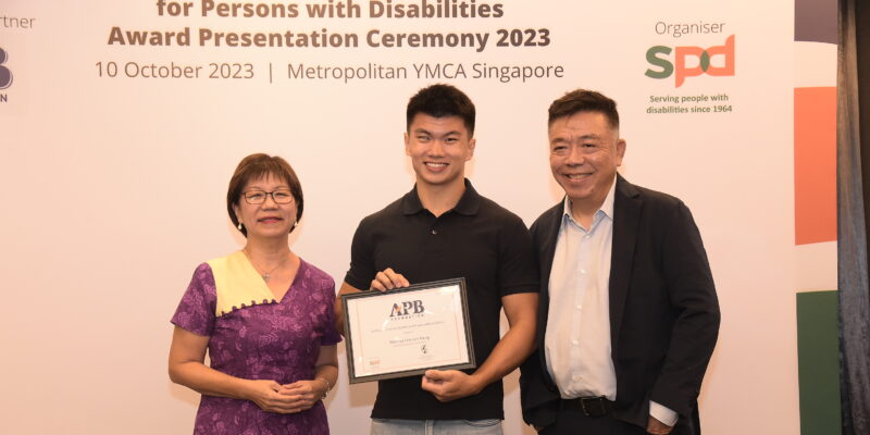 Marcus holding his scholarship, positioned between Ms Denise Phua and Mr Kenneth Choo