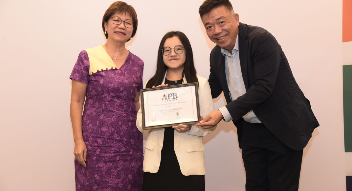 Magdalene holding up her scholarship, standing between Ms Denise Phua and Mr Kenneth Choo