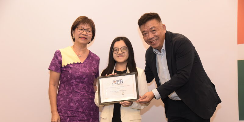 Magdalene holding up her scholarship, standing between Ms Denise Phua and Mr Kenneth Choo