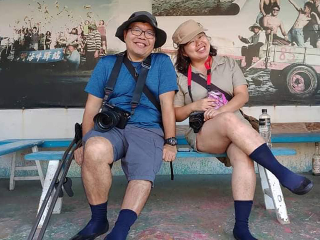 Kee Choon and Ziying in outdoorsy gear, seated on a bench