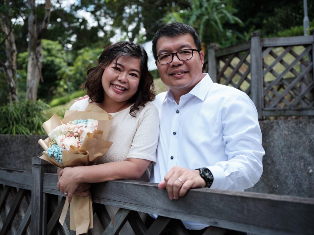Ziying holding onto a bouquet of flowers with Kee Chong beside her, both dressed in white