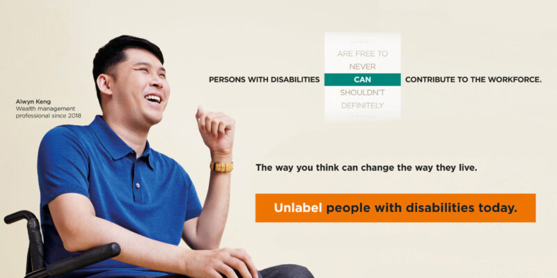 Alwyn in blue collared tee seated in his wheelchair smiling. Tagline People with disabilities can contribute to the workforce. Unlabel people with disabilities today.