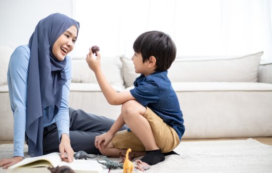 A mother smiling at her son as he holds up a small dinosaur toy