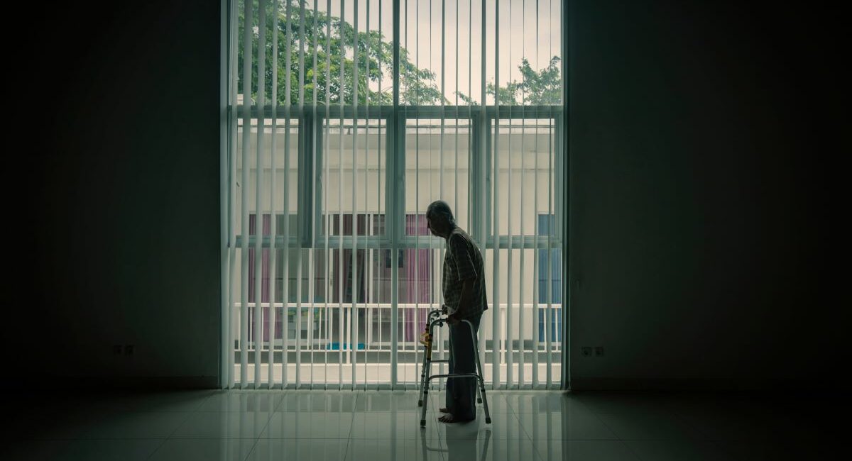 Silhouette of an elderly man using a walking frame