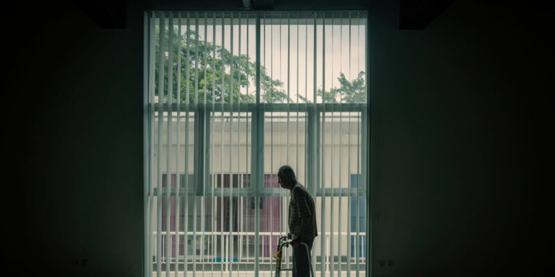 Silhouette of an elderly man using a walking frame