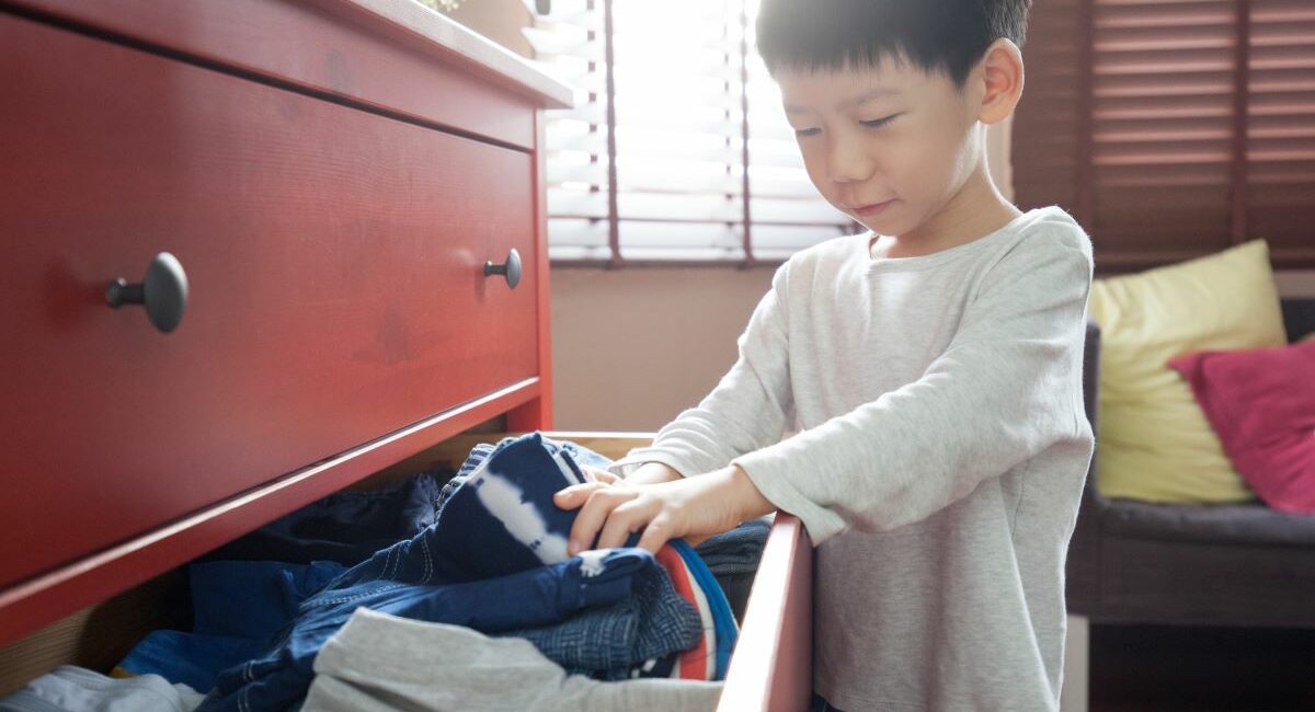 Boy looking for something to wear in a drawer full of clothes