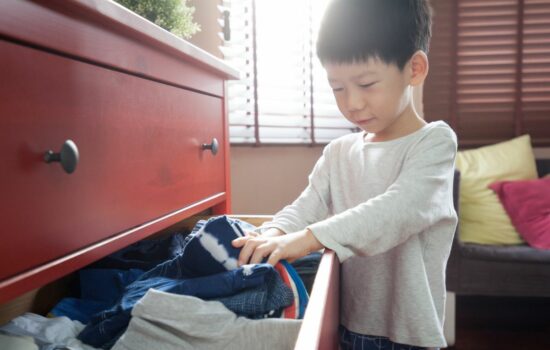 Boy looking for something to wear in a drawer full of clothes