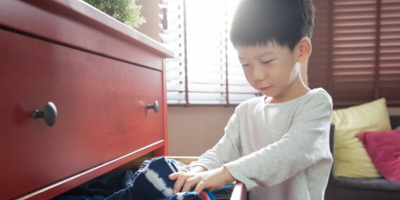 Boy looking for something to wear in a drawer full of clothes