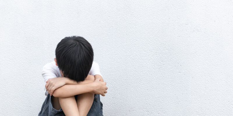 A boy sitting on the ground crying