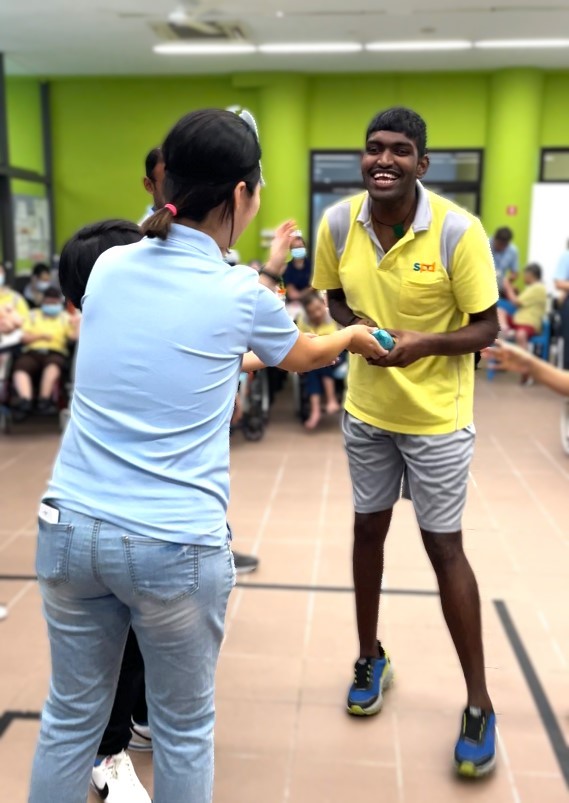 Puvan walks excitedly towards a volunteer to receive a present
