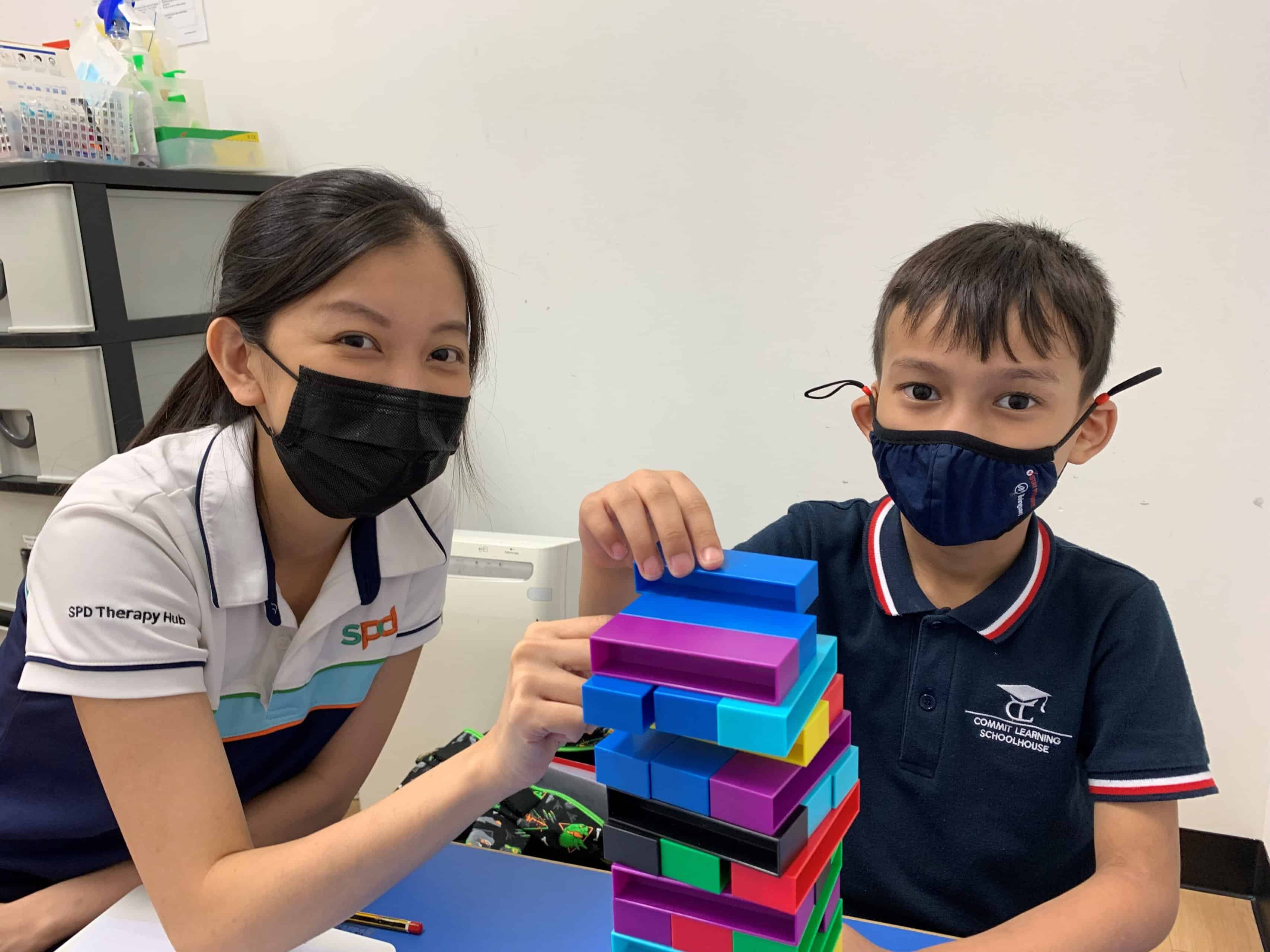 An S P D staff and a young boy playing with some multi-coloured plastic bricks