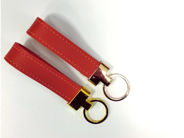 A pair of dark orange S P D Artisan Collab leather key fobs 