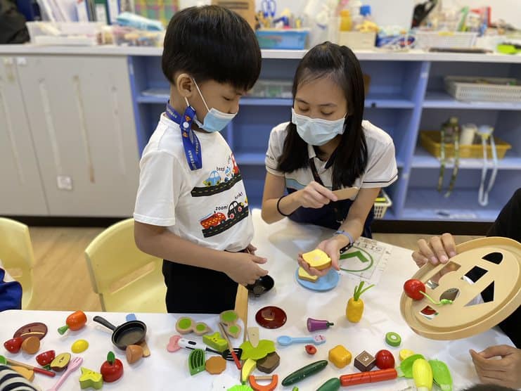 An OT engaging a young client in a tabletop activity during class time