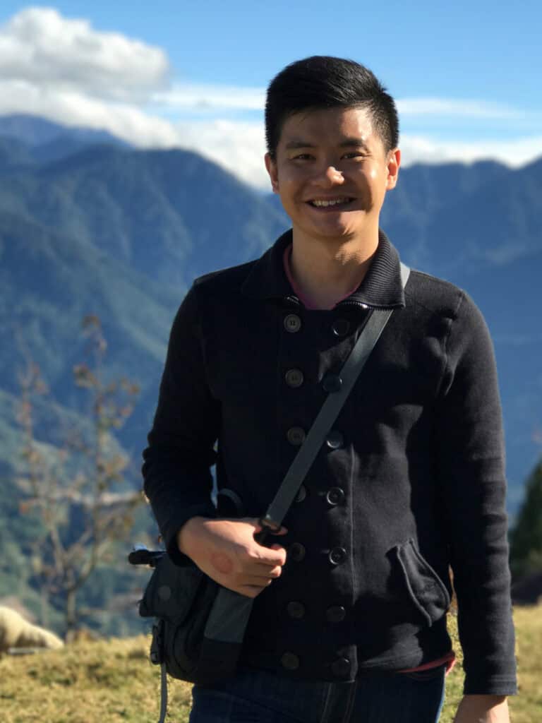 Social worker Alvin in black long sleeve shirt, with mountains and greenery in the background