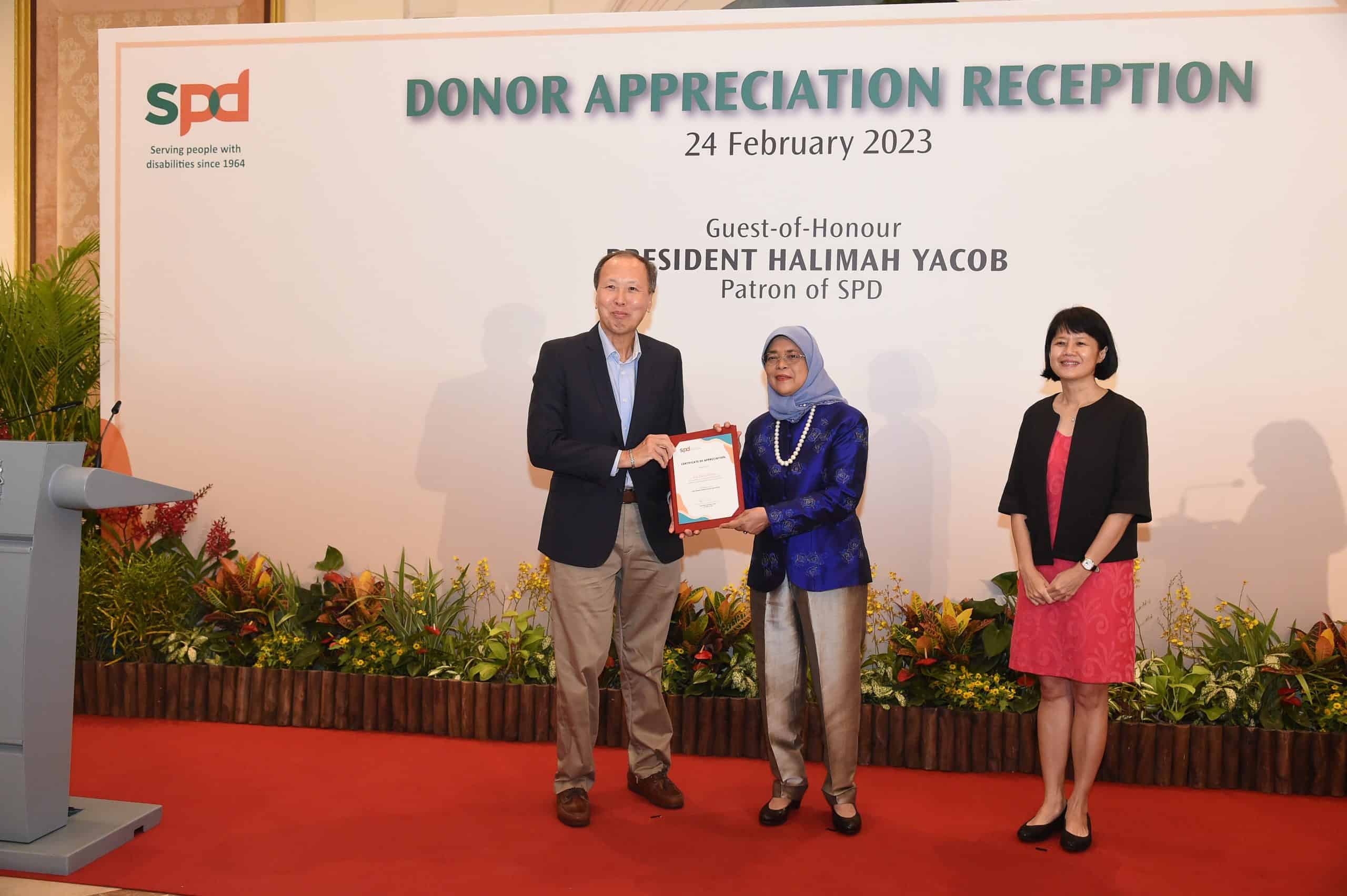 Mr Lee W.C receiving a certificate from President Halimah Yacob 