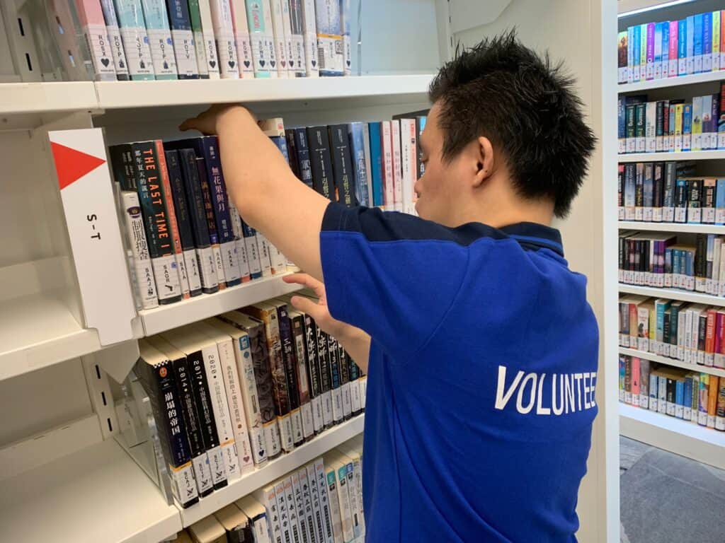 ESH client Shawn helping to sort out books at a library