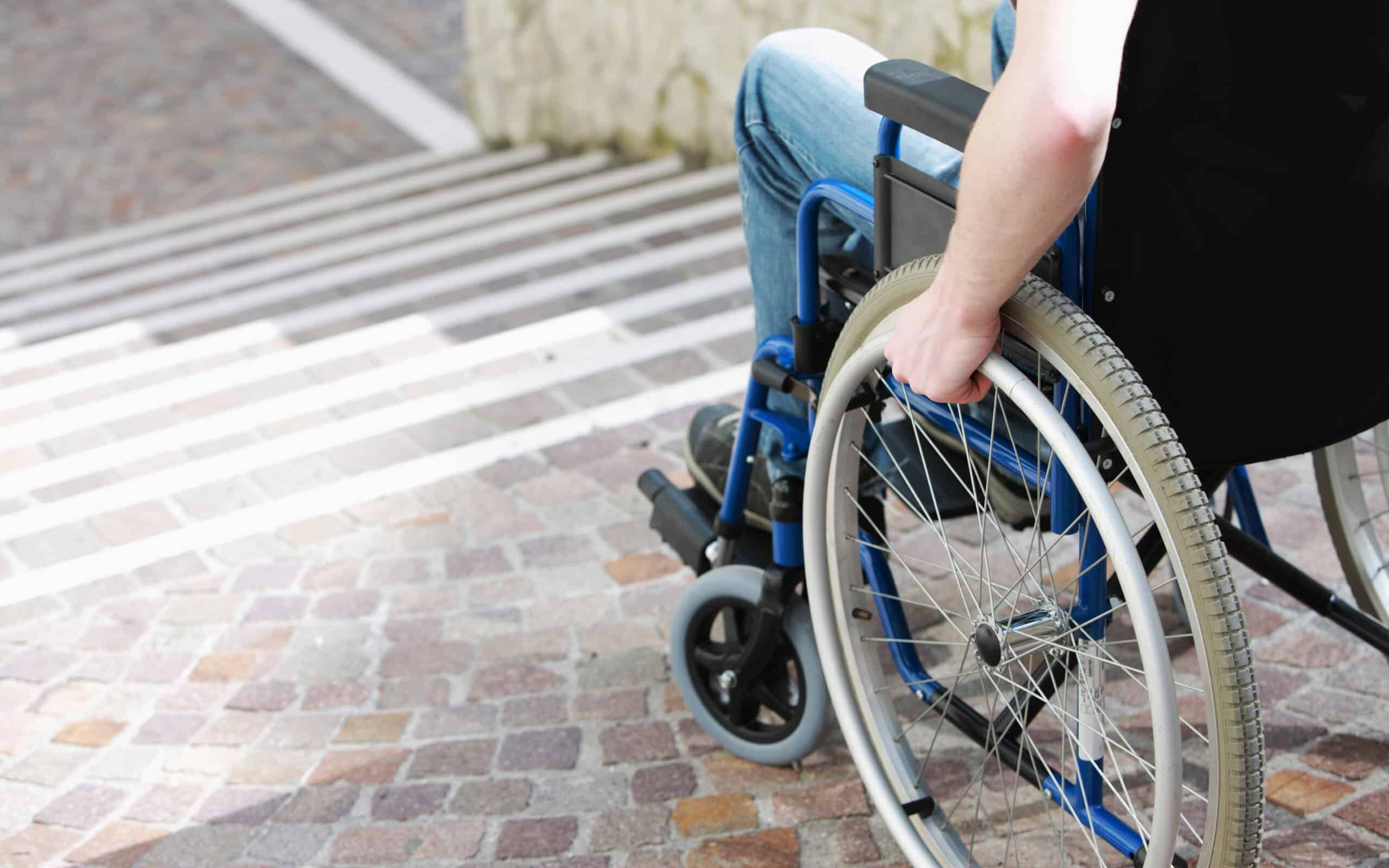 A wheelchair user stopping in front of a flight of stairs