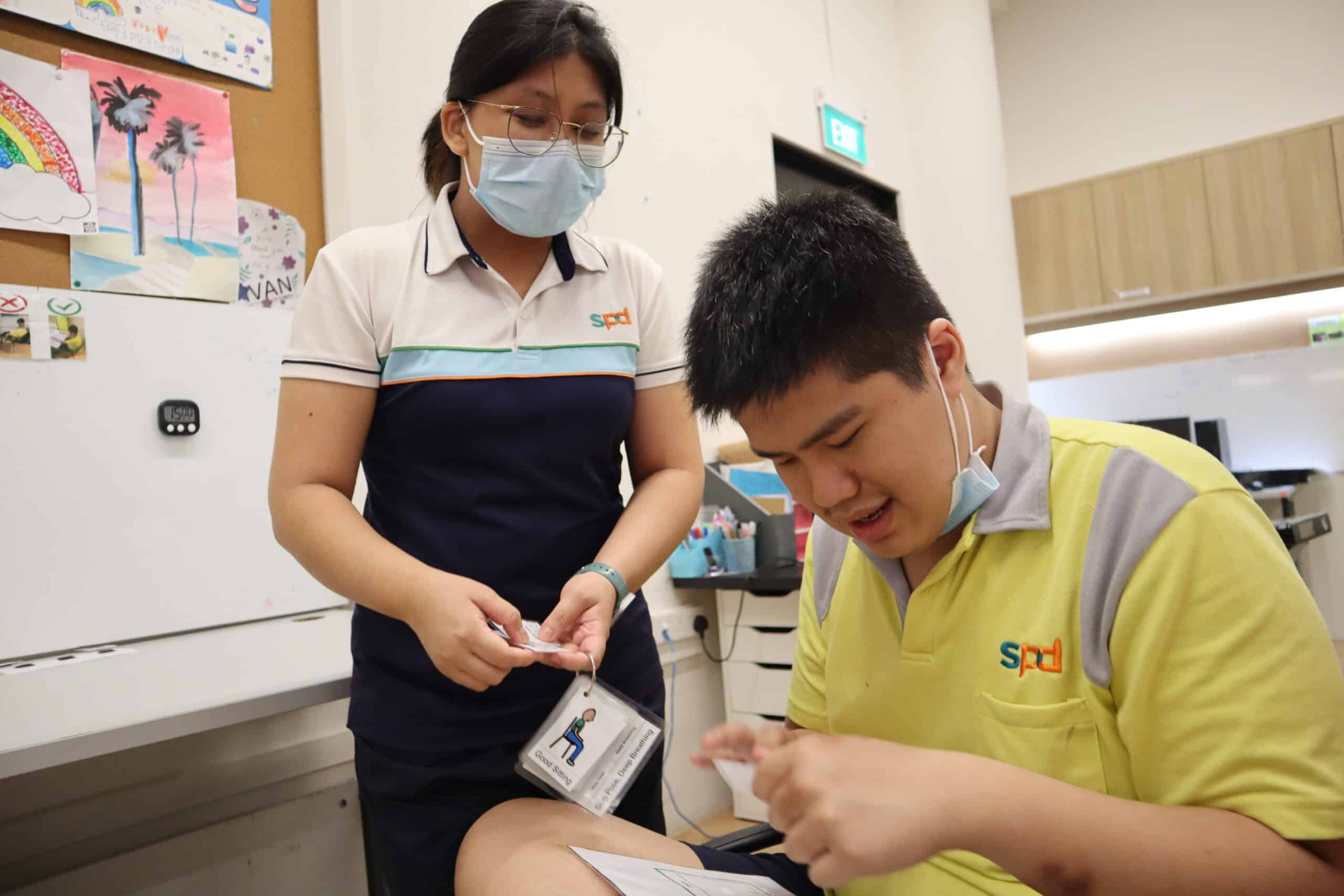 A training officer engaging Hong Yun with picture cards