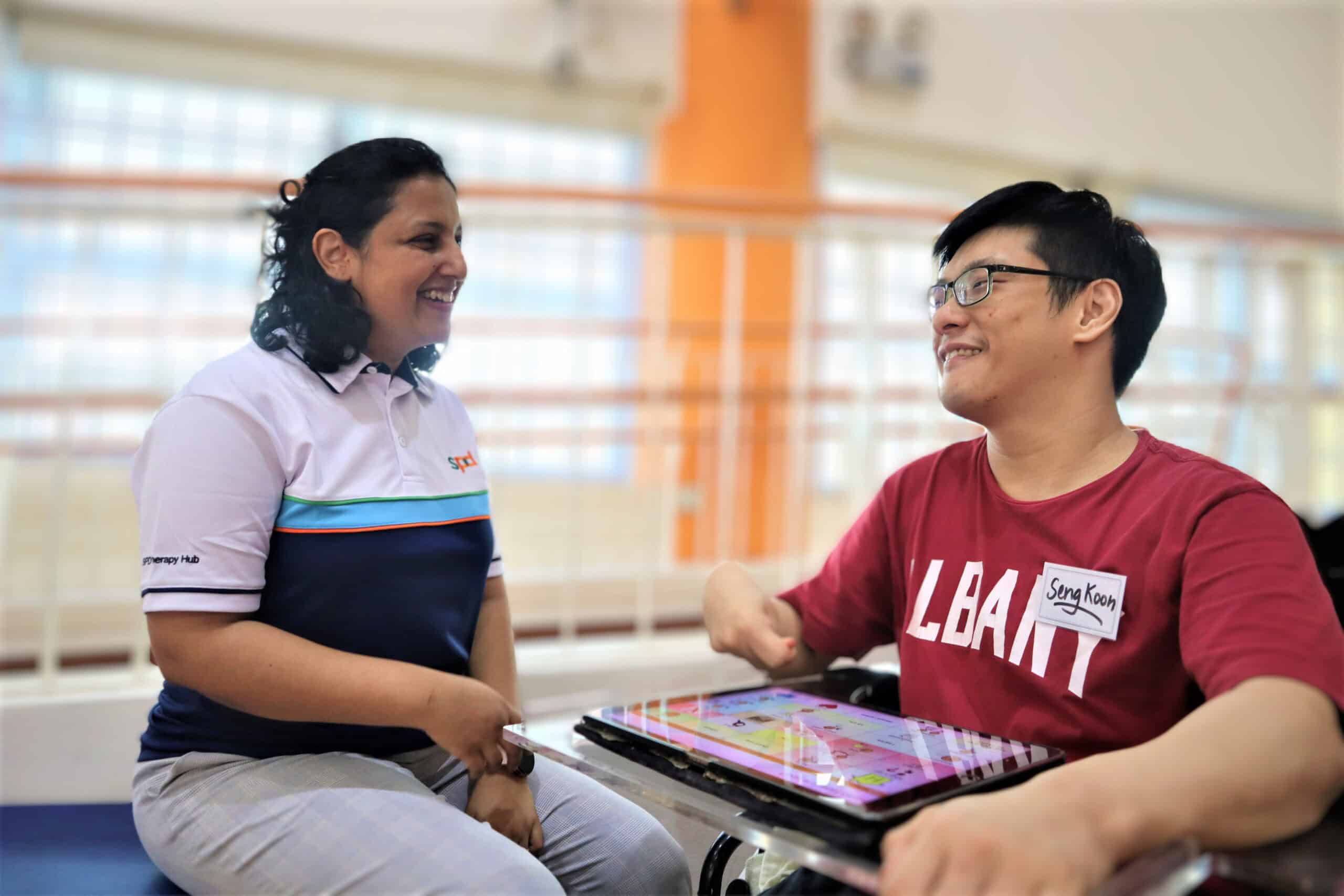 Tanushree having a chat with Seng Koon who has an A A C app open on his tablet