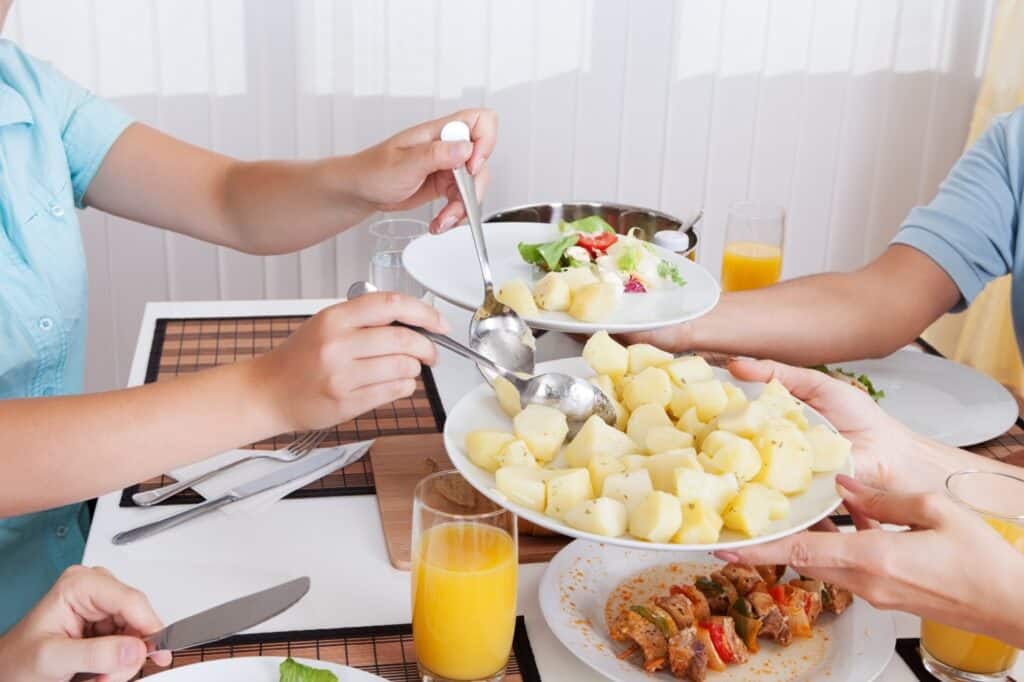 A family passing food around the table in a sharing plate