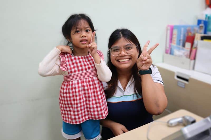 Teacher Isma and a young girl posing happily for the camera.