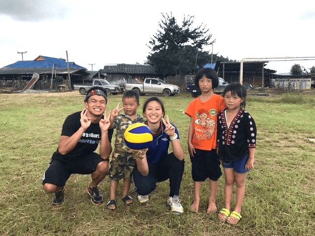 Marcus smiling and posing with one other female volunteer and 3 children