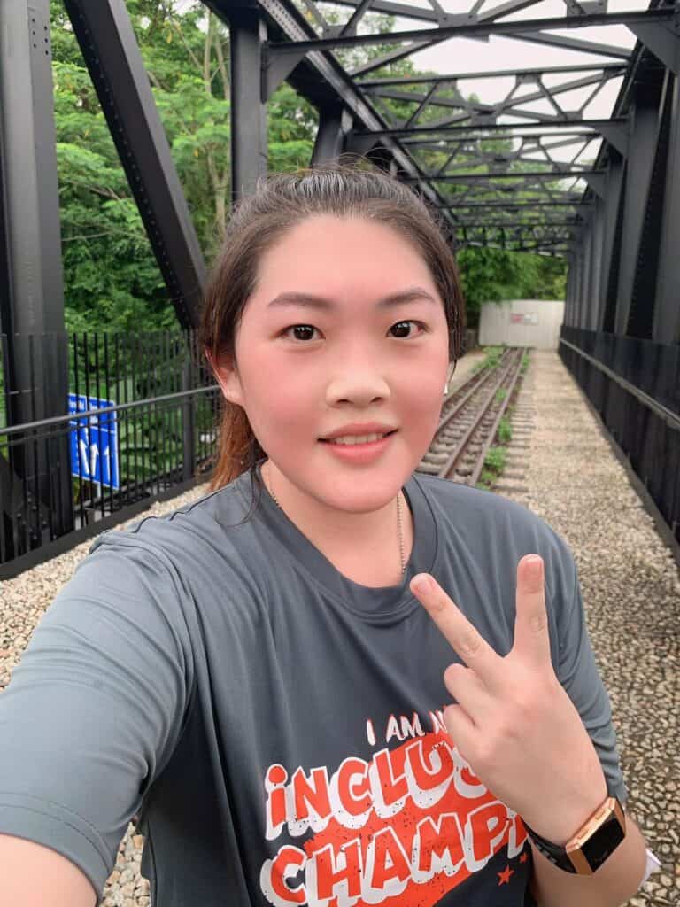 Walk participant Ms Helern Tan in the grey "I am an inclusion champion" SPD Ability Walk and Run tee giving a V sign