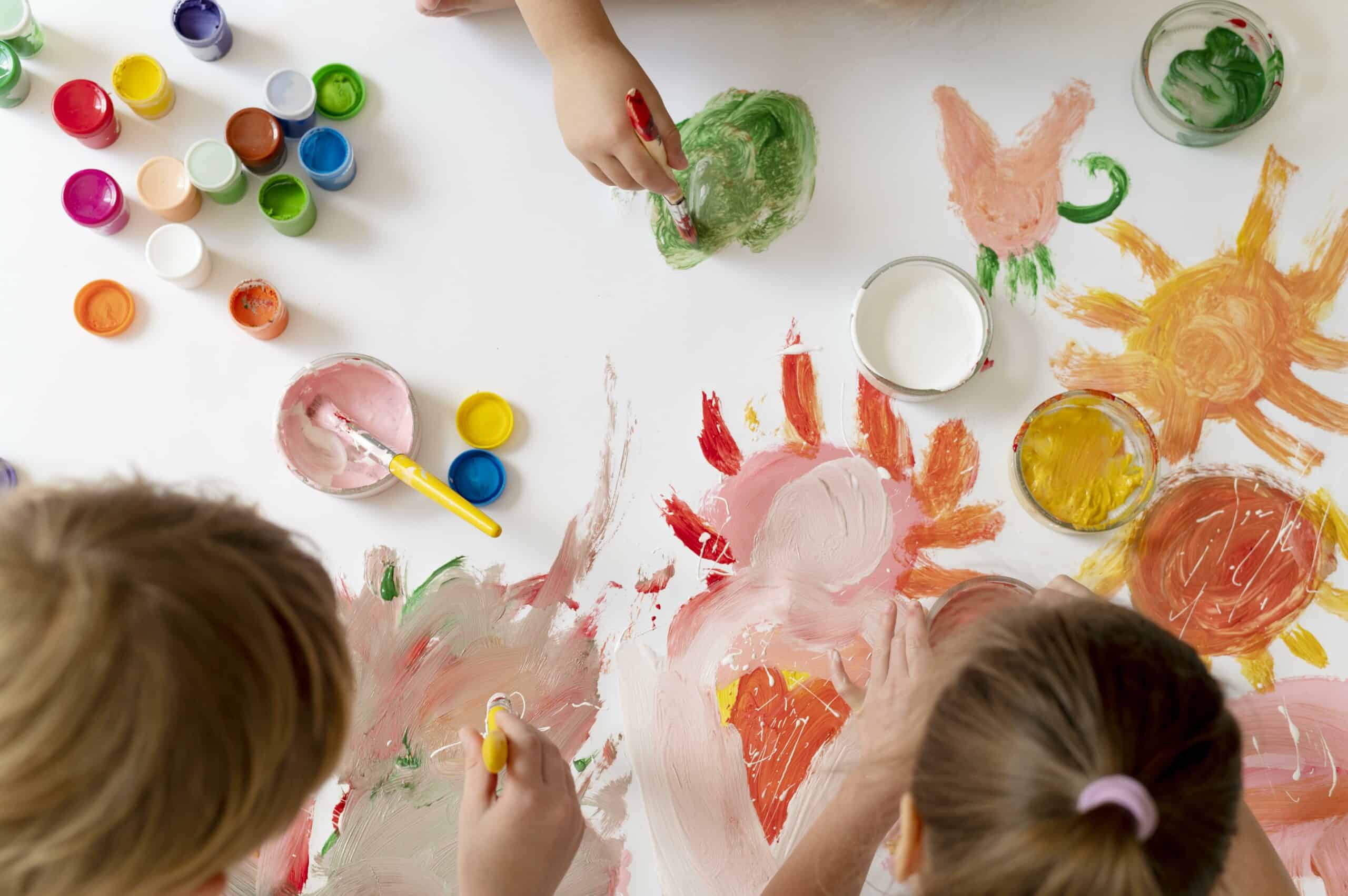 Top view of children drawing shapes using watercolour