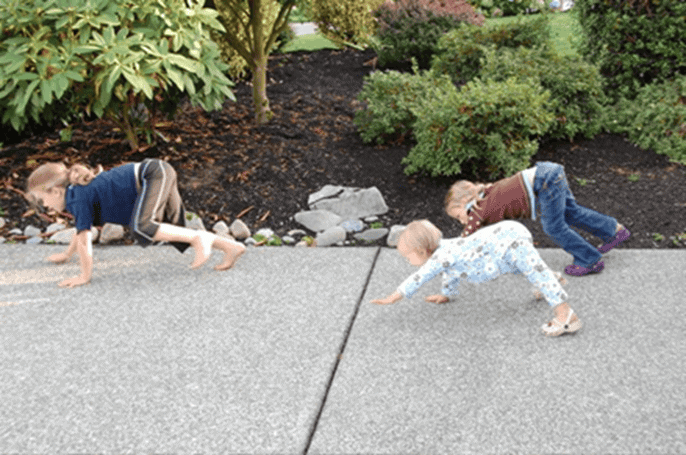 Three children moving on the ground on their hands and legs.