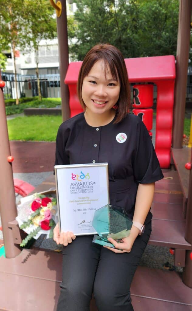 Senior educational therapist Felicia Ng smiling for the camera, while holding the certificate and award