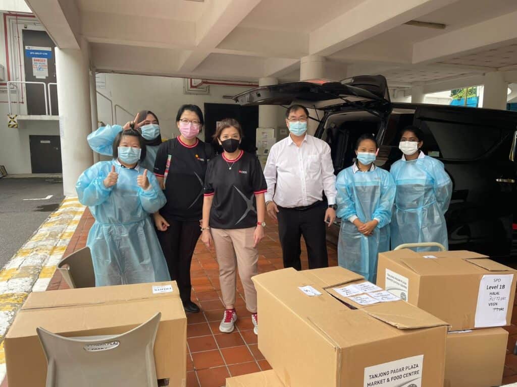 A group of people standing behind boxes of meals