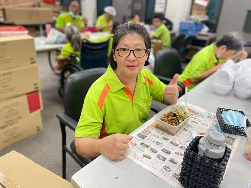 A woman posing with her meal, showing thumbs-up