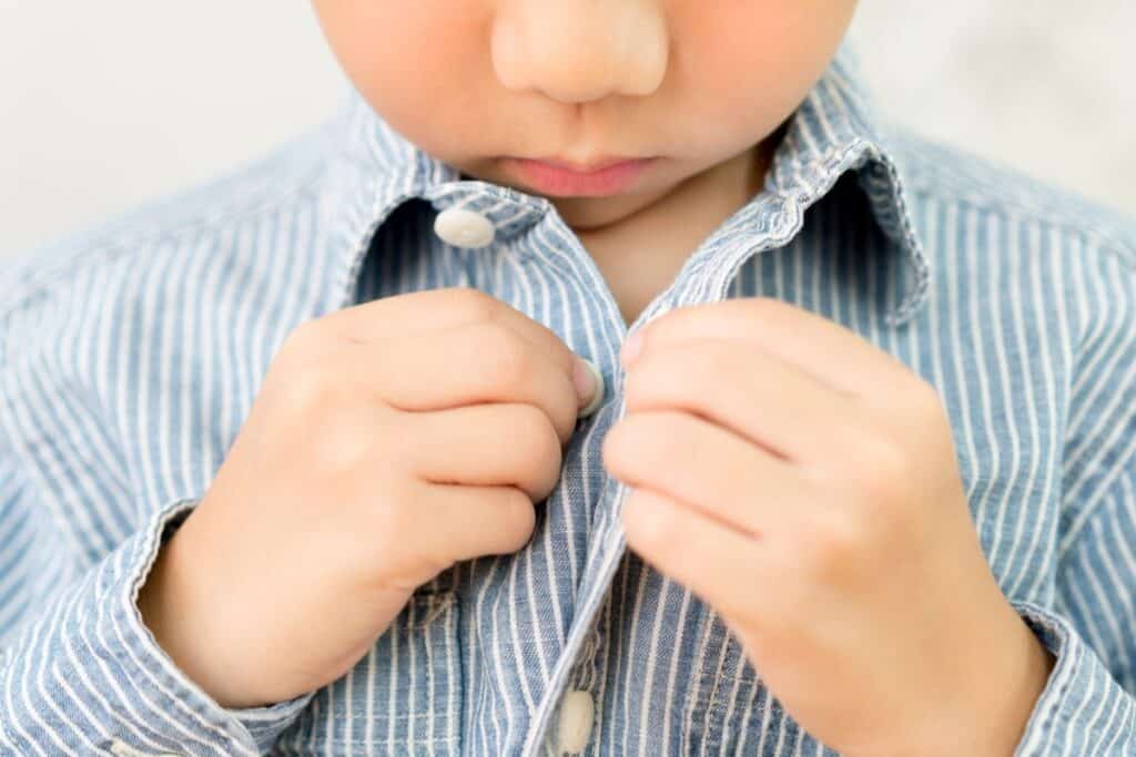 A child buttoning his shirt