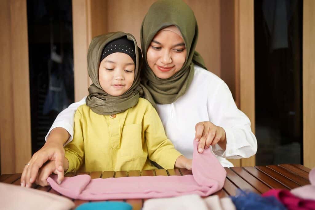 A woman folding clothes with a girl