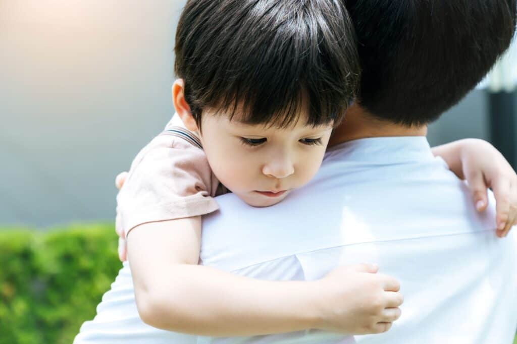 A man holding a sad-looking boy