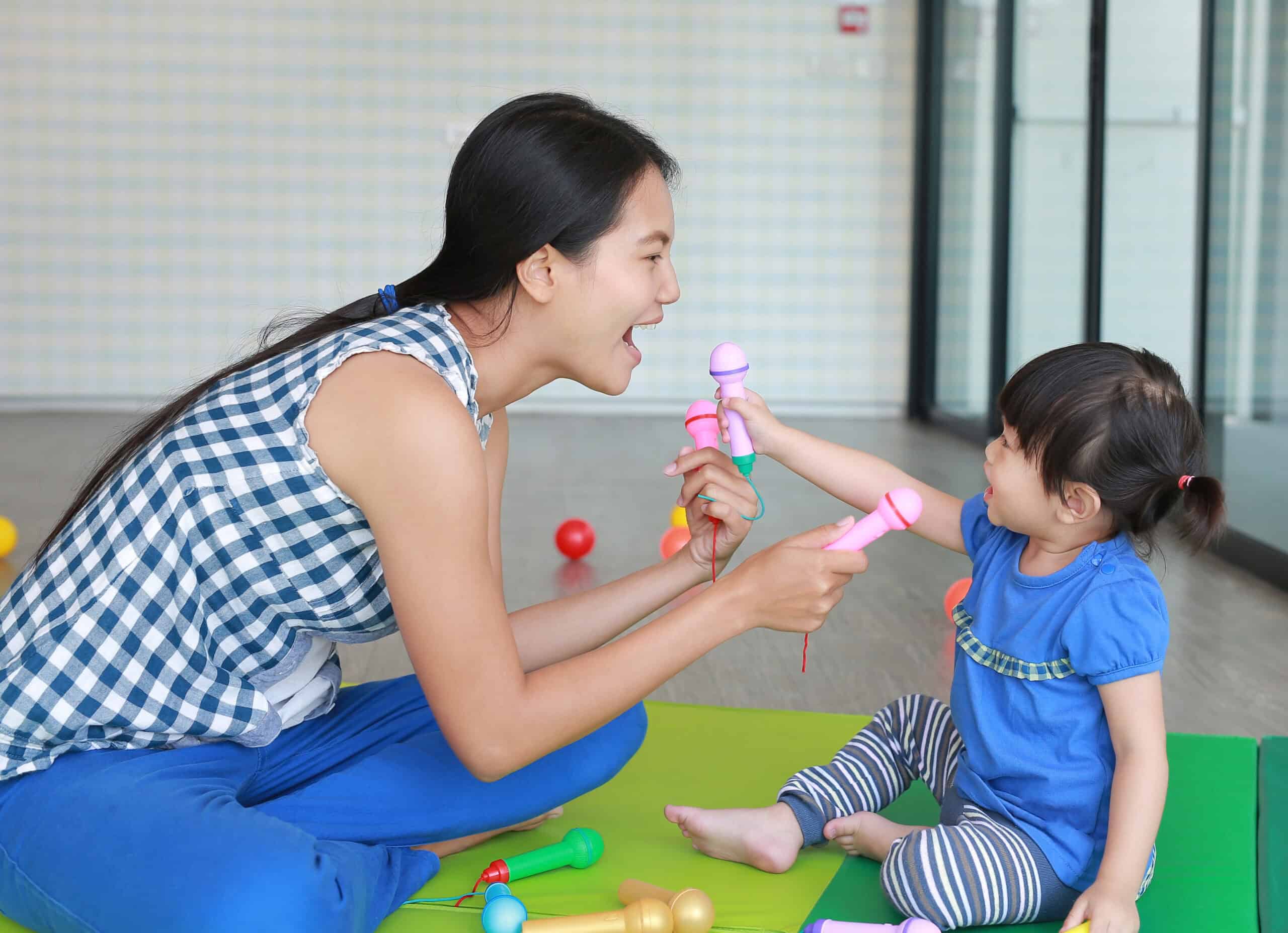 A mother holding a toy mic to a toddler