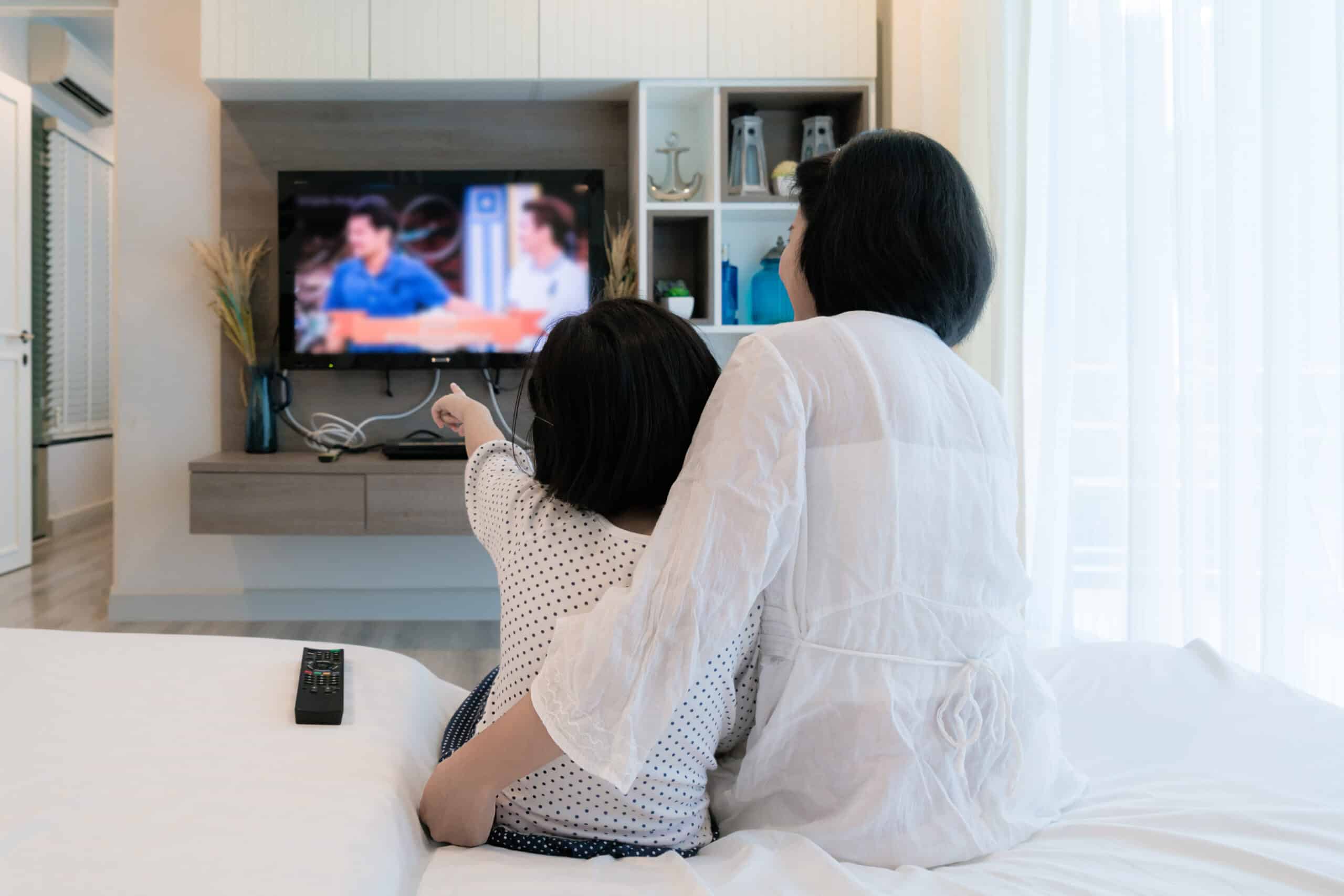 A mother watching TV with her daughter.