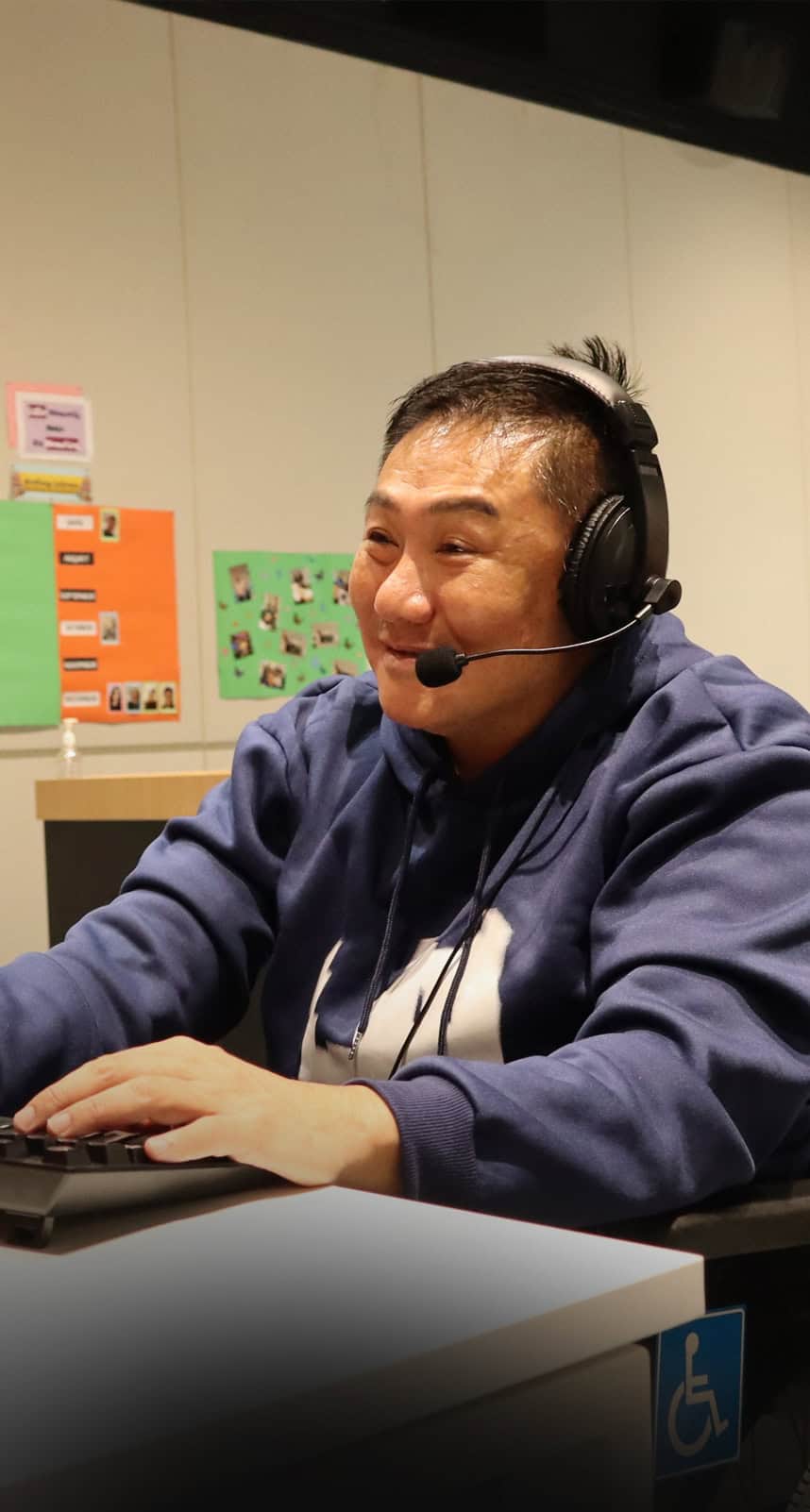 A wheelchair user wearing a headset working on his computer