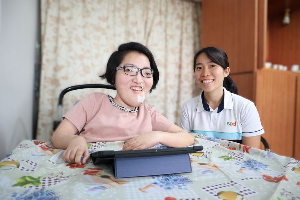 A young woman with a feeding tube in her nose with an S P D social worker.