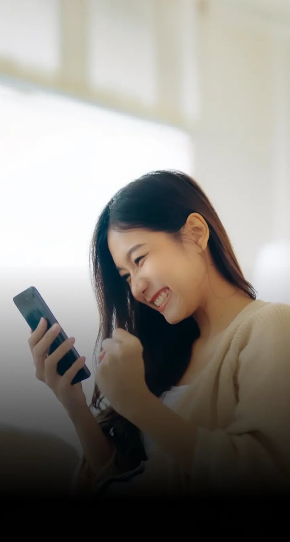 A woman smiling and looking at her mobile phone.