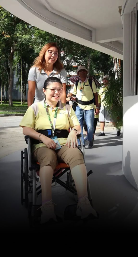 An S P D volunteer pushing and a young woman in her wheelchair as her peers from the S P D Day Activity Centre follow behind.