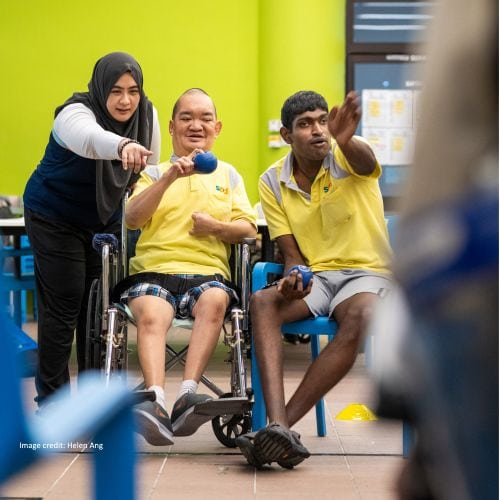 An S P D staff guiding a wheelchair user on playing adapted boccia