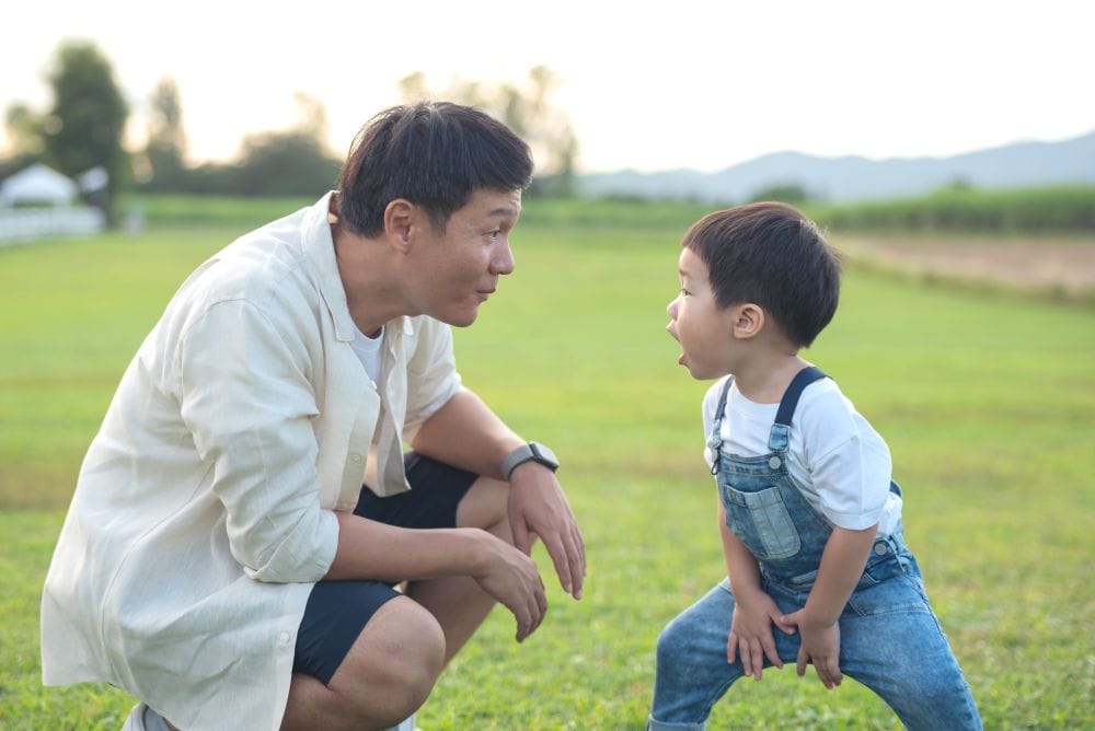 A man speaking with a boy against the backdrop of an open field