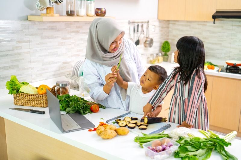 A mother guiding a boy and a girl in preparing some ingredients on a kitchen countertop for cooking.