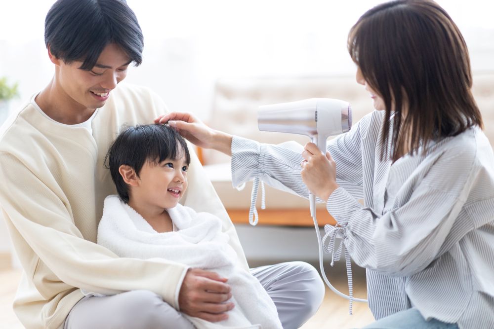 Parents drying the hair of a boy using a hair dryer