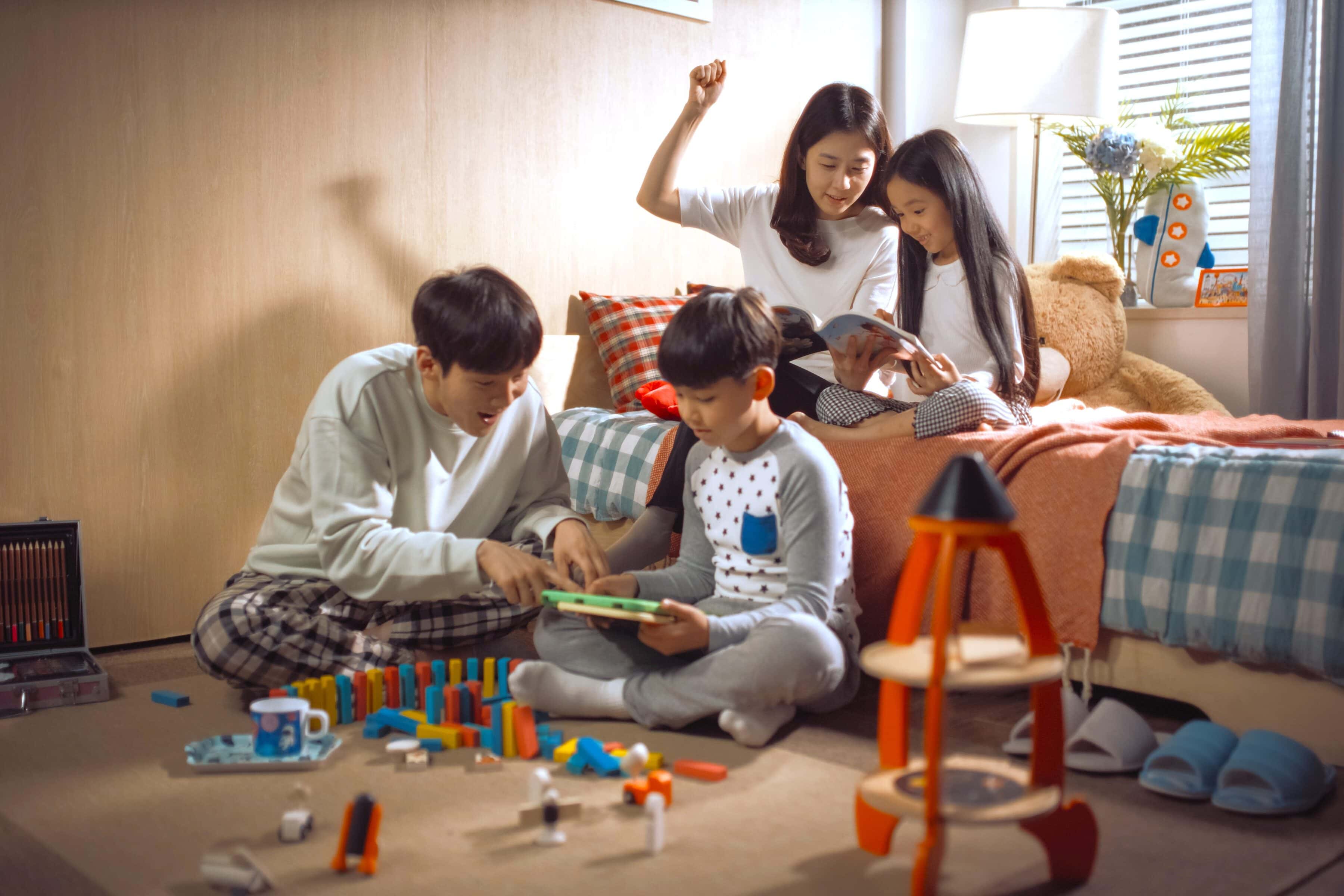 A family of four reading on their tablet and book.