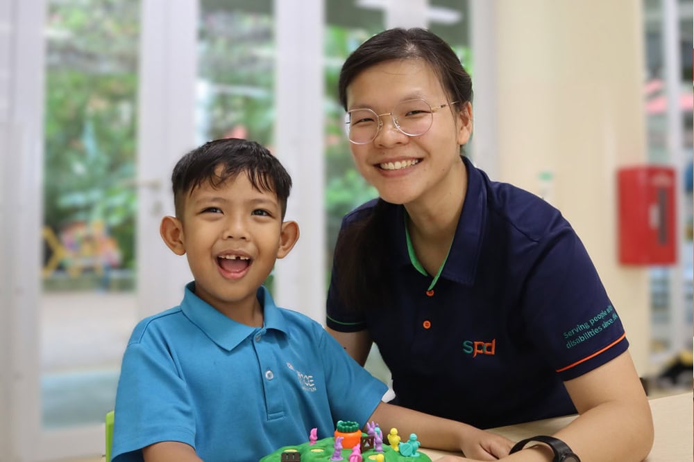 Development Support and Learning Support 1 An occupational therapist and a young boy smiling happily as they work on some tabletop activities.