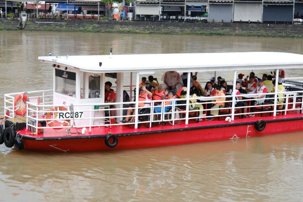 SPD Ability Walk 2025 Celebrates 10th Anniversary with Heritage-Themed Scavenger Hunt and First-Ever Accessible River Cruise 7 Wheelchair users and participants on board river cruise, waving happily